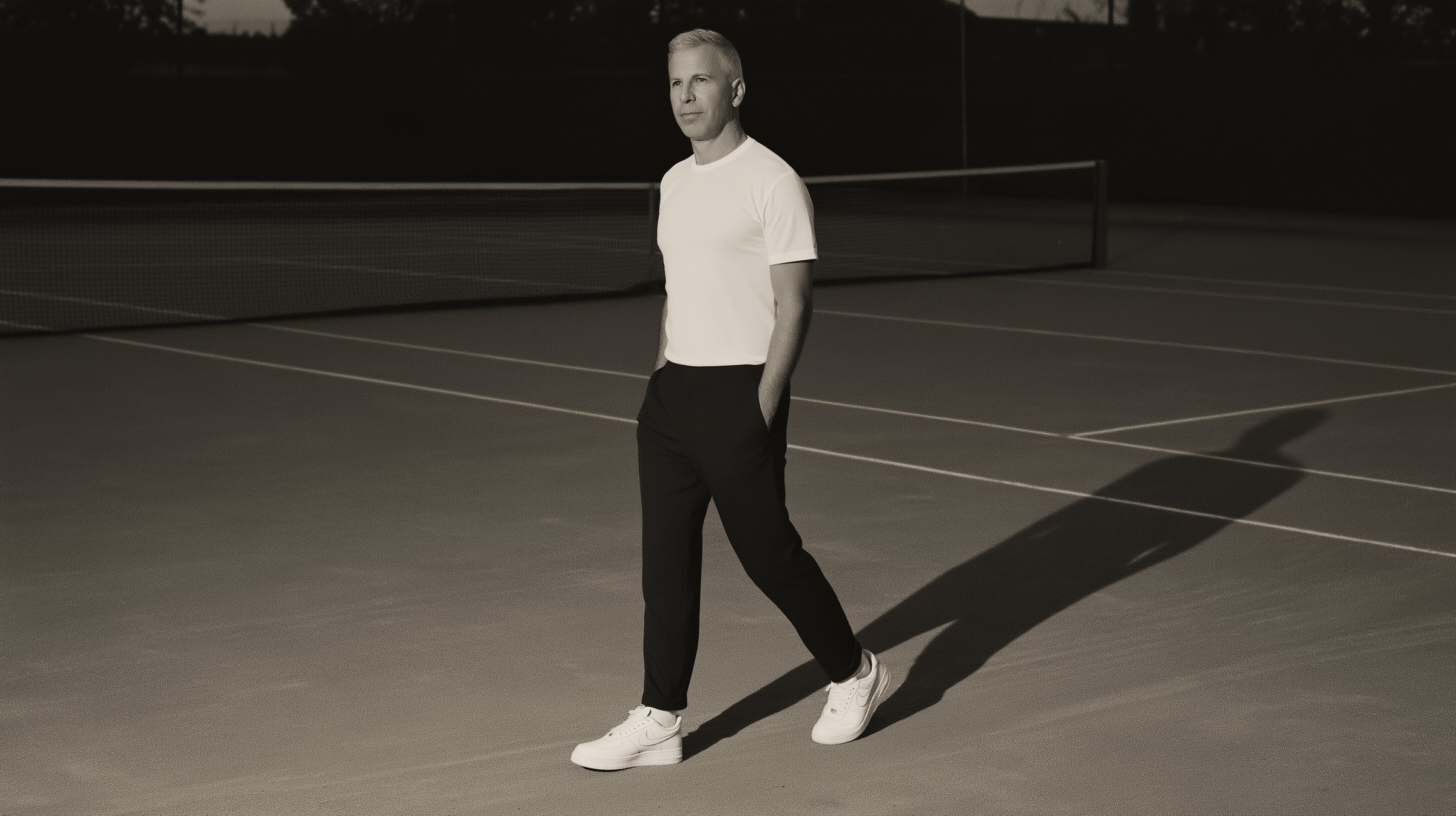 Chris Kypriotis walking across a tennis court at dusk